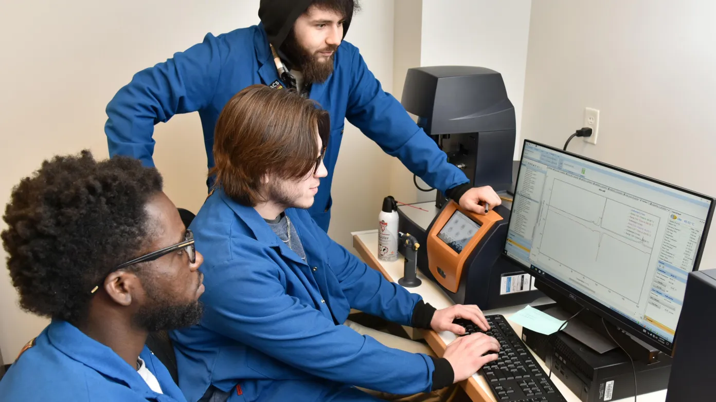 three students working on a computer