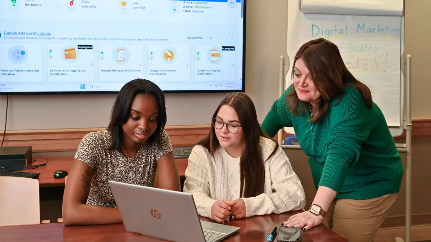 faculty helping students with digital marketing certification looking at a laptop