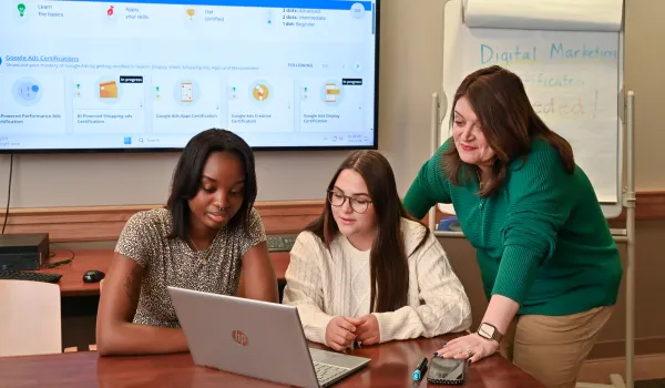 faculty helping students with digital marketing certification looking at a laptop