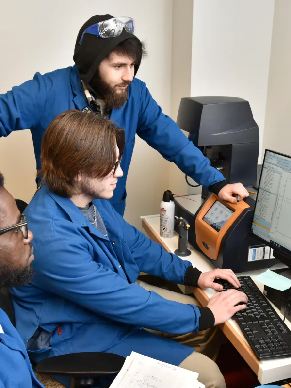 three students working on a computer