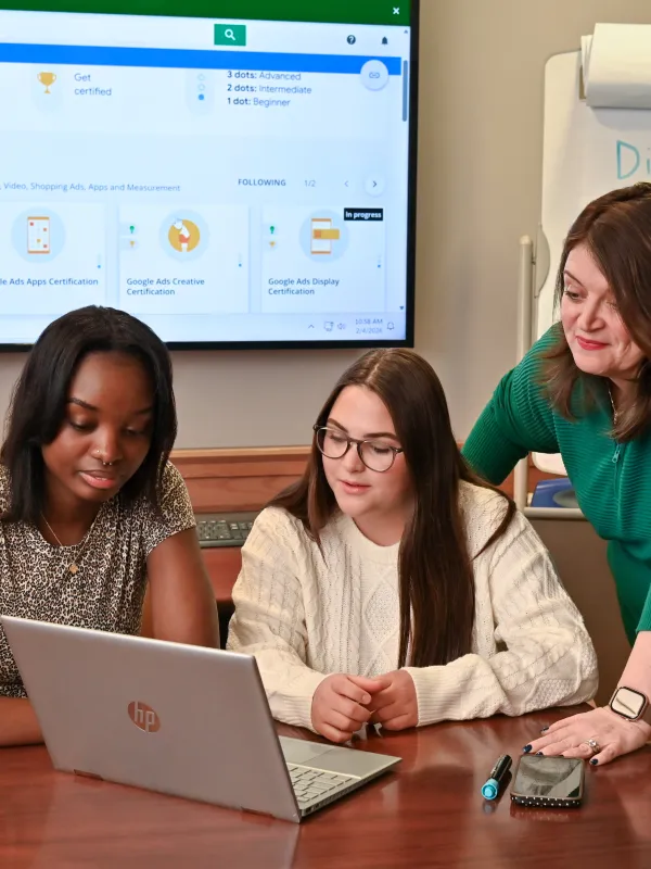 faculty helping students with digital marketing certification looking at a laptop